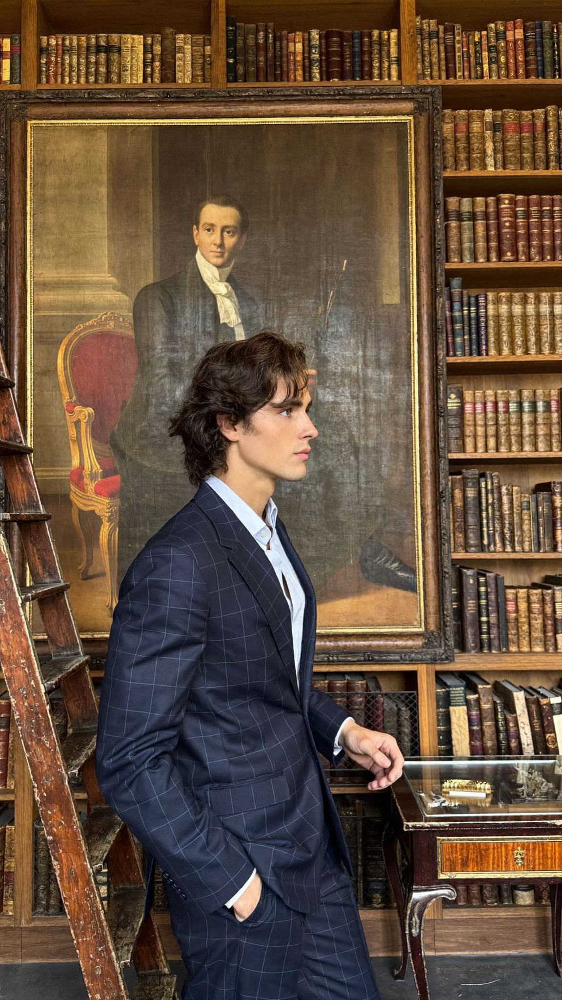 Man in a suit standing among bookshelves